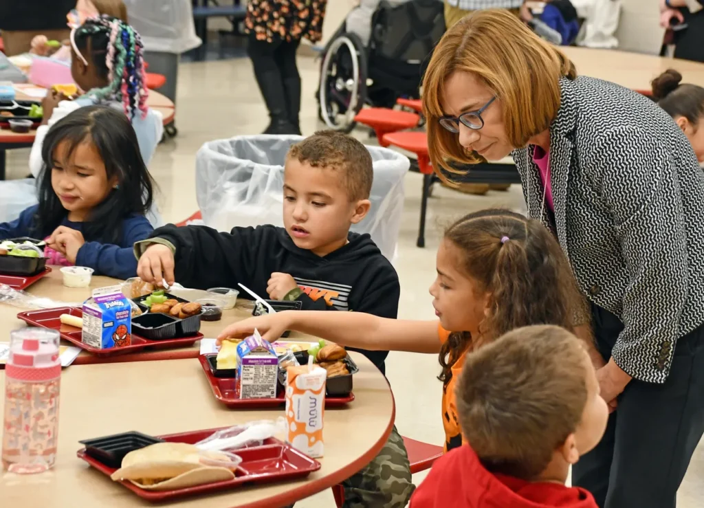A NUT employee checking in on students sitting and eating at the table.