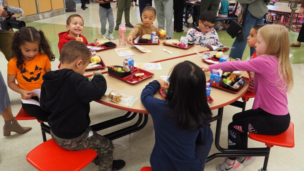 A group of kids sitting at a round circle cafeteria table.