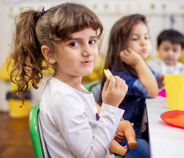 A girl taking a bit of an apple slice.
