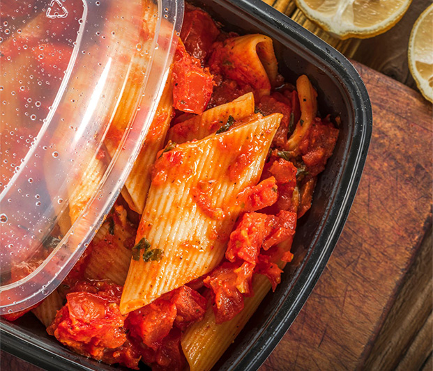 A close up of red pasta in a to-go container.