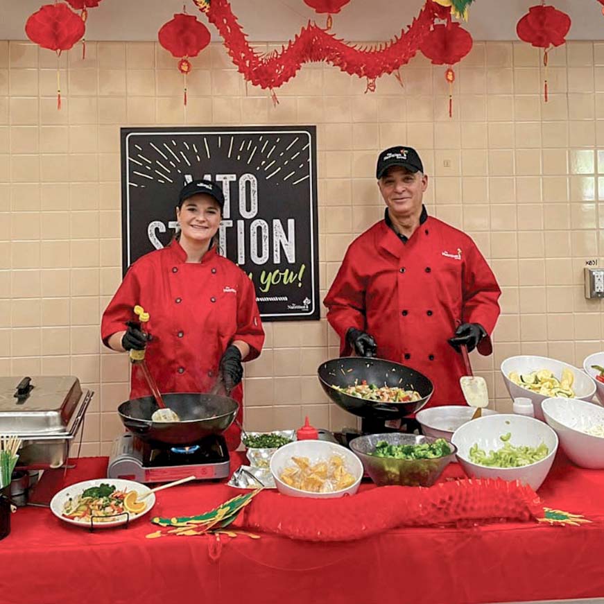 Two chefs in red chef's coats. Cooking Chinese noodles.