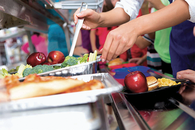 A server in a serving lane filling a tray for a student.