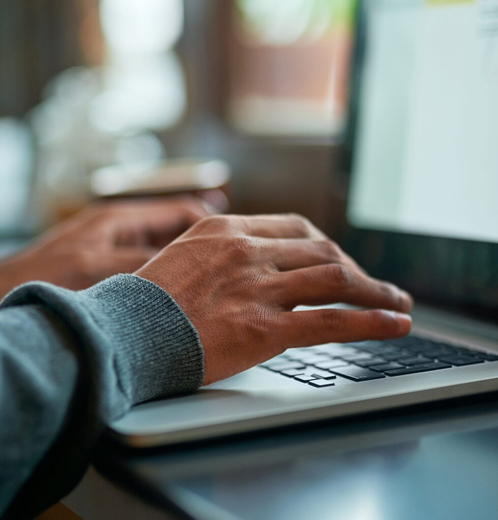 A close up of hands typing on a laptop.