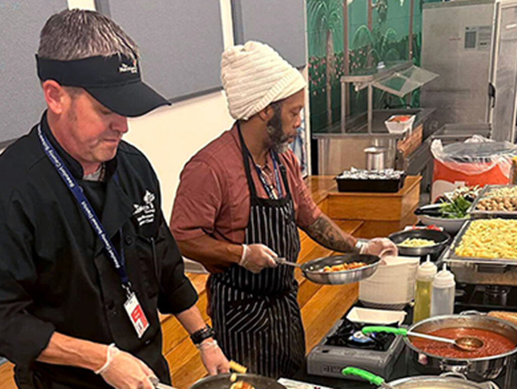Two NUT workers cooking and prepping the serving lane.