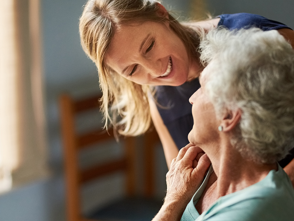 A woman caretaker looking over the shoulder of an older woman.