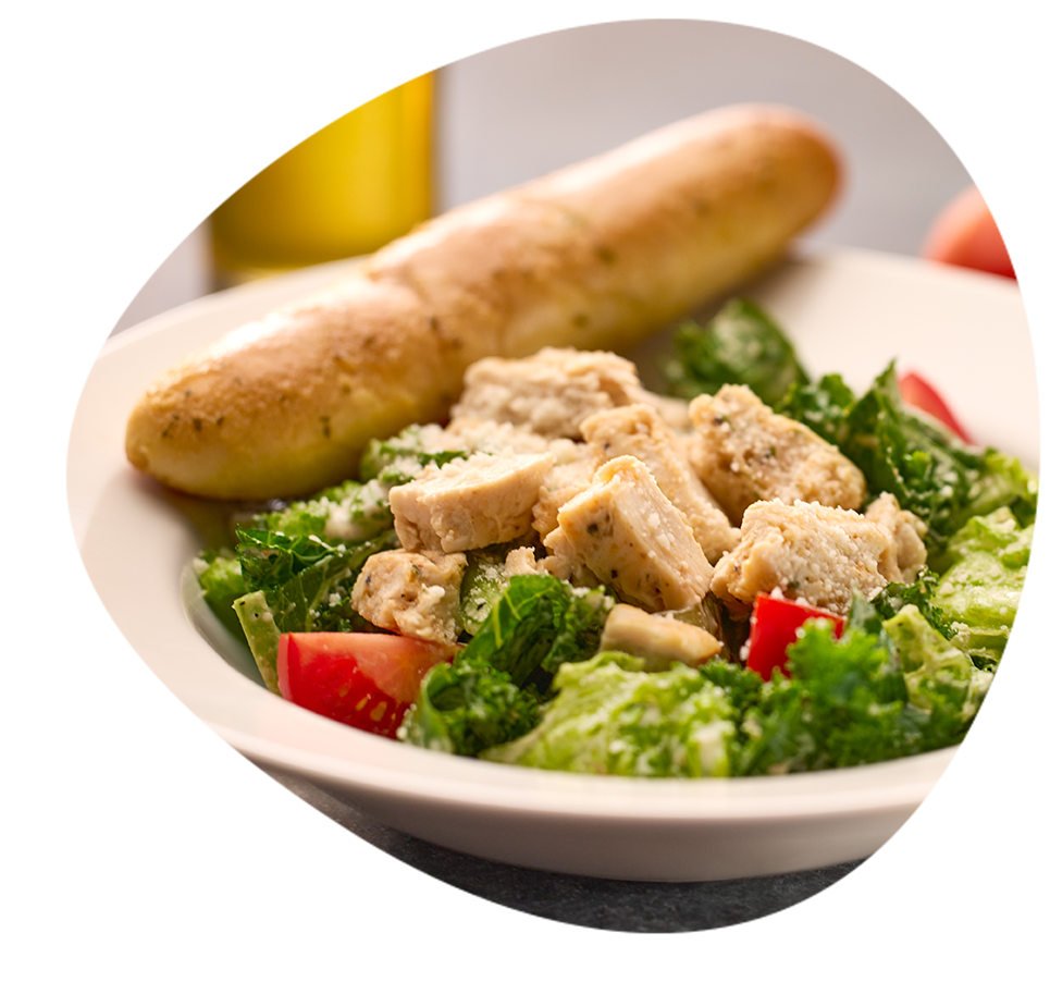 A close up of a Caesar Salad with a breadstick.